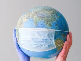 hands with latex gloves holding a globe with a face mask