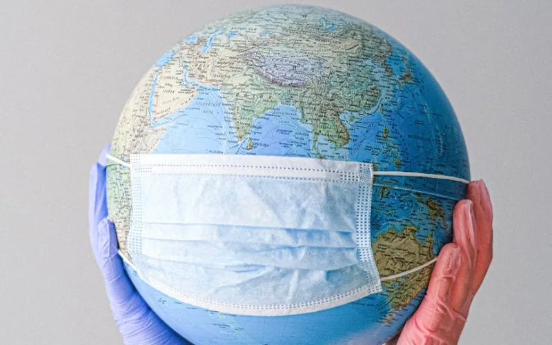 hands with latex gloves holding a globe with a face mask