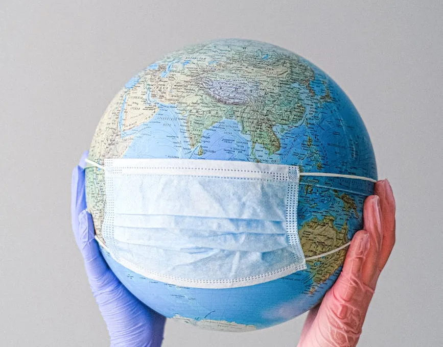 hands with latex gloves holding a globe with a face mask