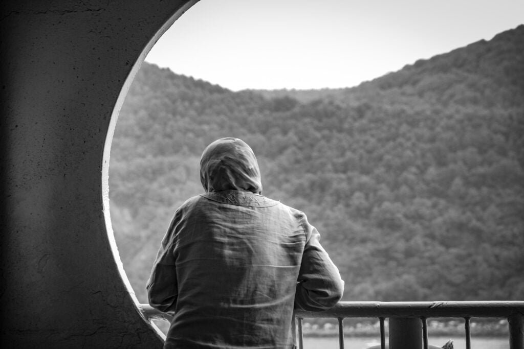 female wearing hijab standing balcony black white