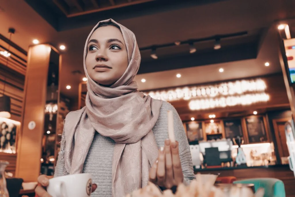 A girl in a headscarf sits in a cafe and dine alone