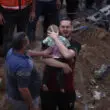man picking up palestinian child from rublle