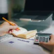 a person sitting at a desk with a calculator and a notebook