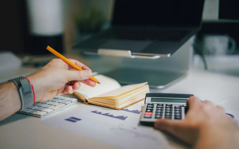 a person sitting at a desk with a calculator and a notebook