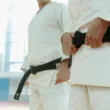 Close Up Shot of Two People Wearing Karategi and Black Belt