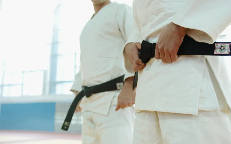 Close Up Shot of Two People Wearing Karategi and Black Belt