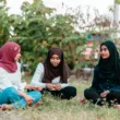 Muslim women sitting on grass in park and talking