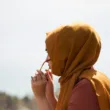 women in brown headdress putting eyeglasses in tilt shift photography