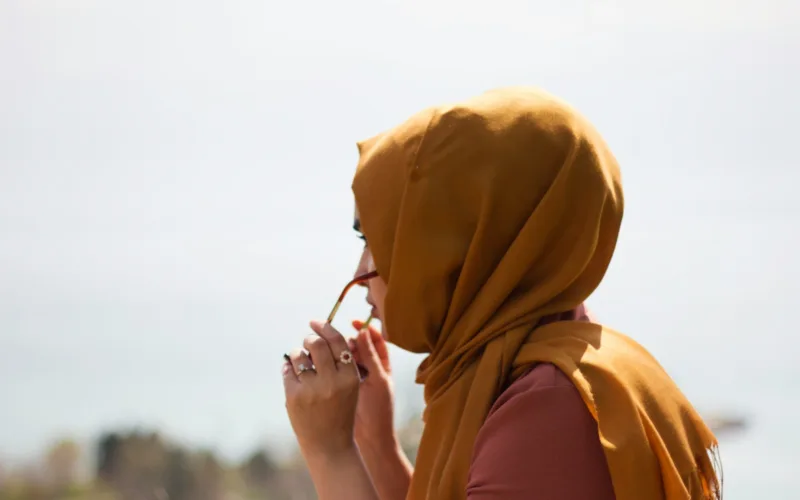 women in brown headdress putting eyeglasses in tilt shift photography