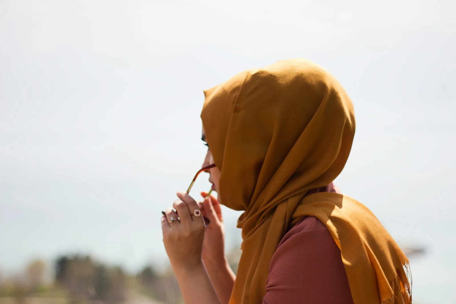 women in brown headdress putting eyeglasses in tilt shift photography