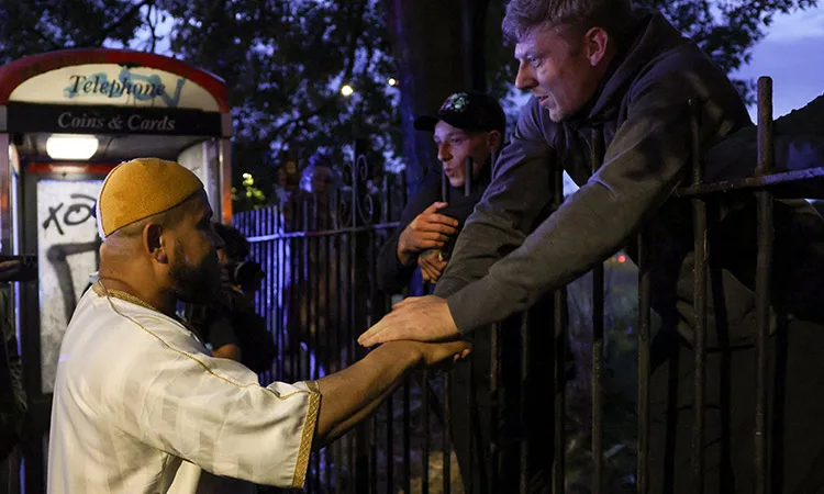 People speak with a Muslim man near a protest outside a mosque in Liverpool, Britain