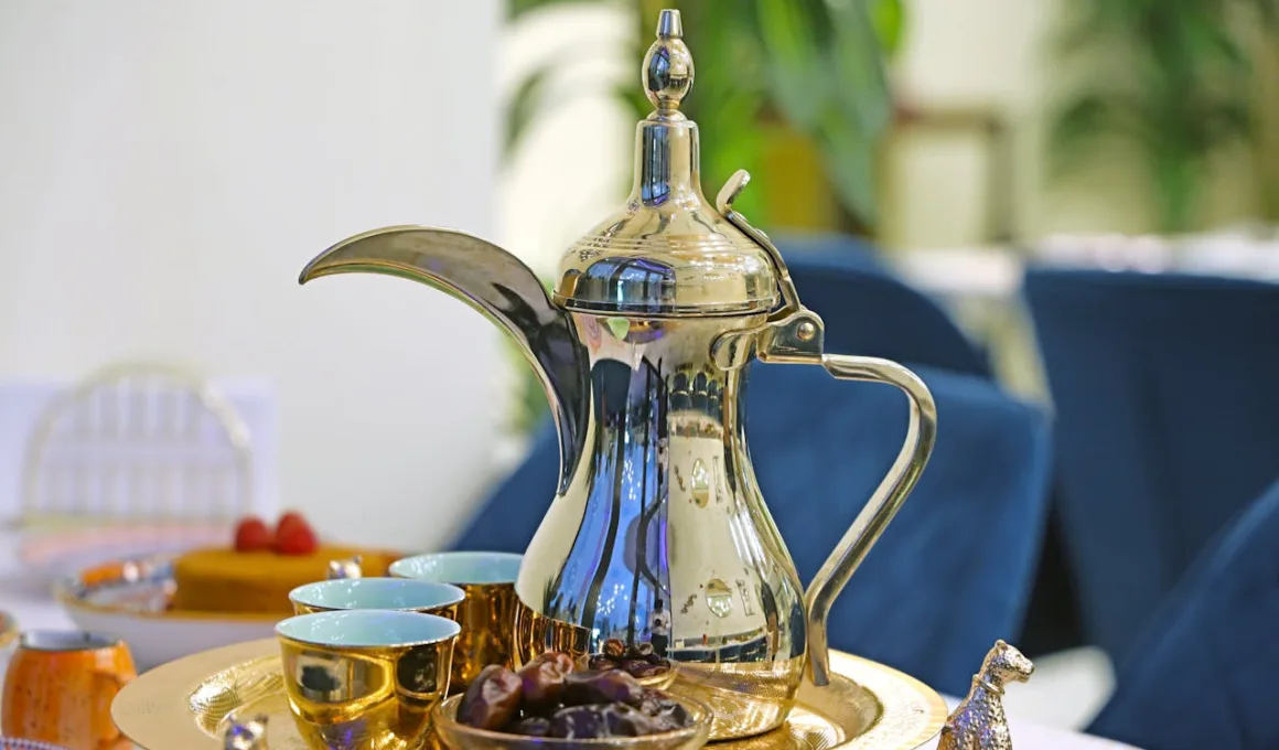 A silver tea pot sits on a tray with a plate of food