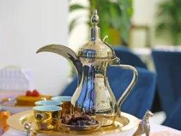 A silver tea pot sits on a tray with a plate of food