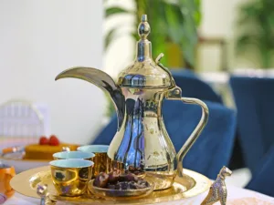 A silver tea pot sits on a tray with a plate of food