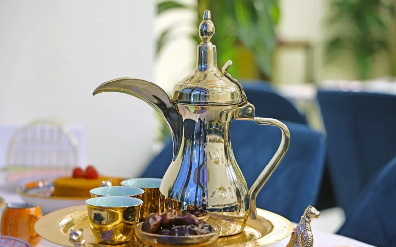 A silver tea pot sits on a tray with a plate of food