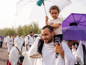 hajj pilgrims 2024 with kid on shoulders