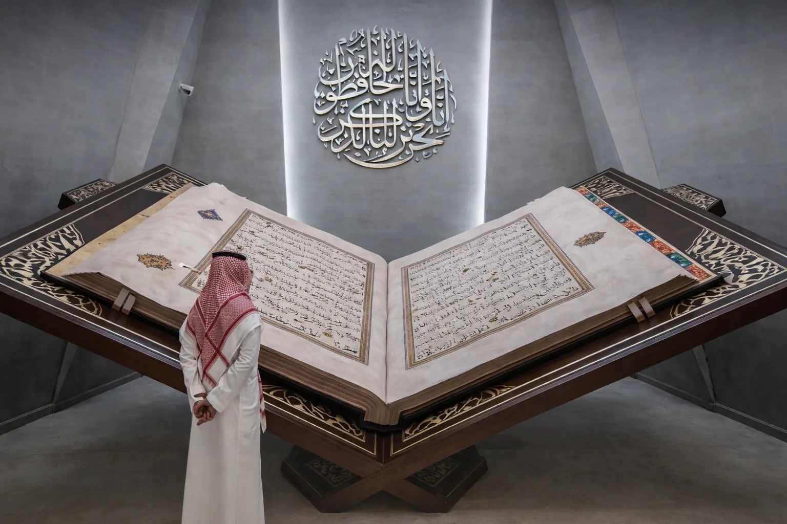 man stands in front of world's largest quran in Makkah 2026