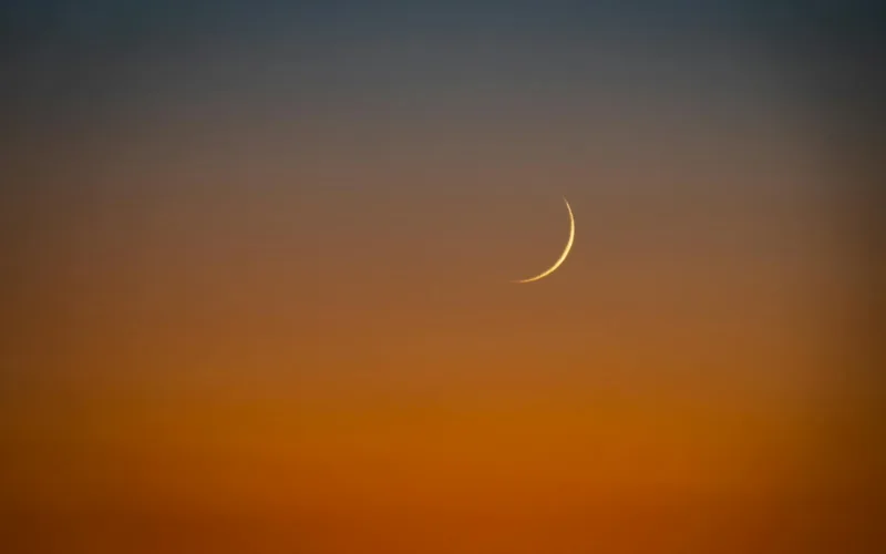 crescent moon over vibrant sunset sky